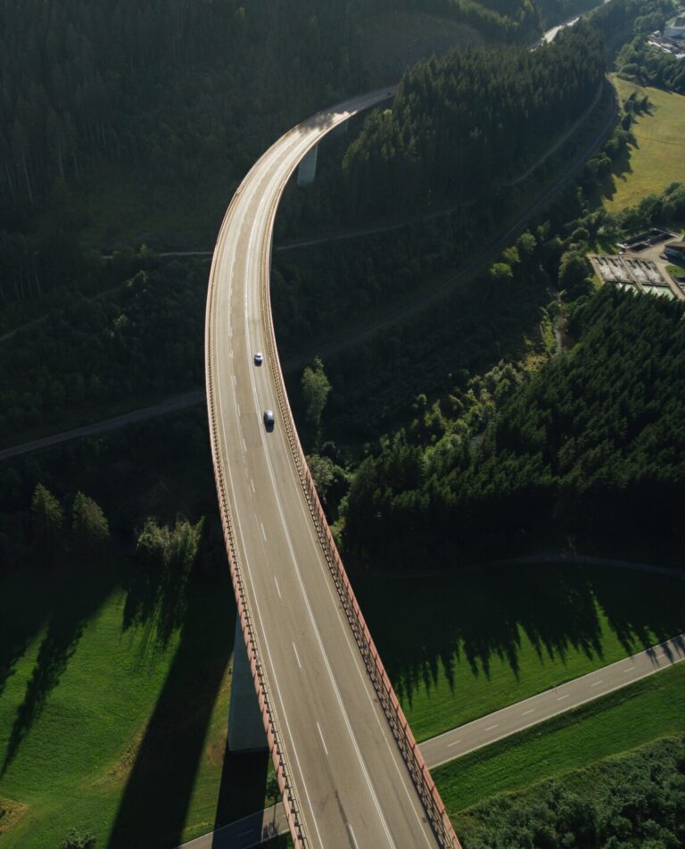 Luftaufnahme von Autos, die über eine Brücke durch einen wunderschönen grünen Wald fahren